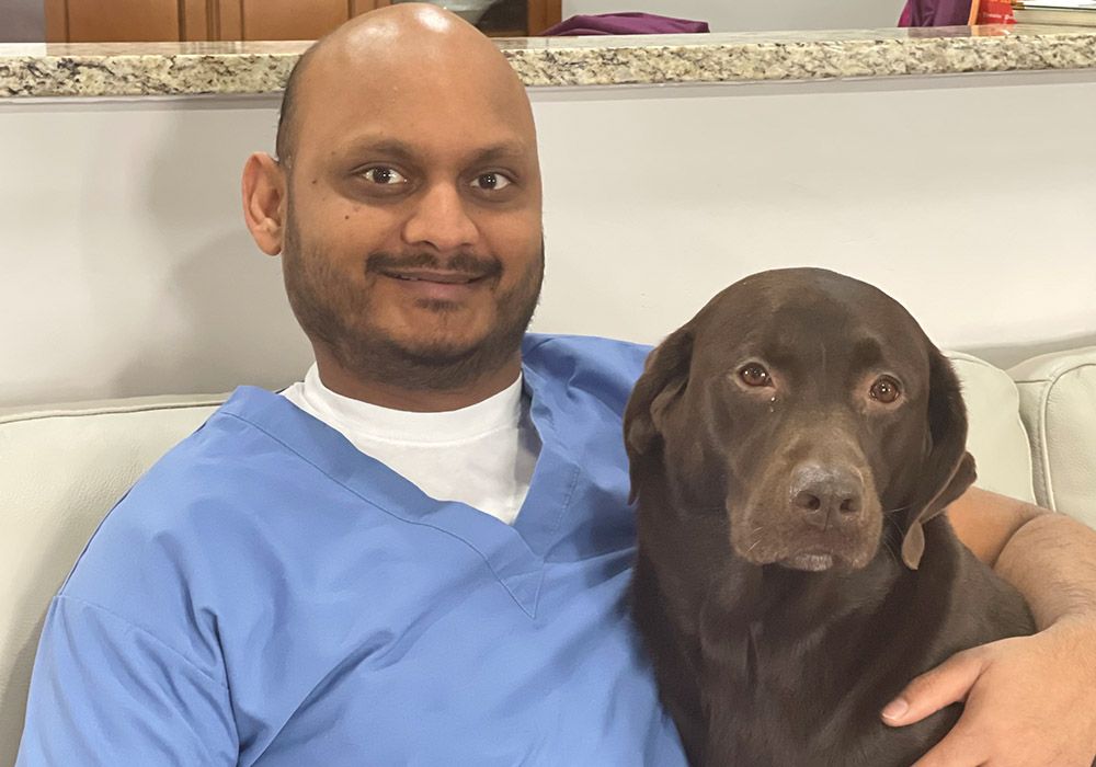 pet urgent care of st peters vet hugging a chocolate labrador dog